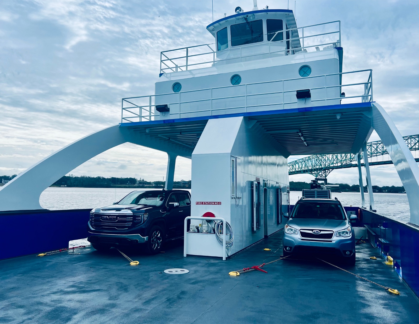 A pickup truck and an SUV parked on the open cargo deck of the Island Hot Shot, seen from the bow ramp
