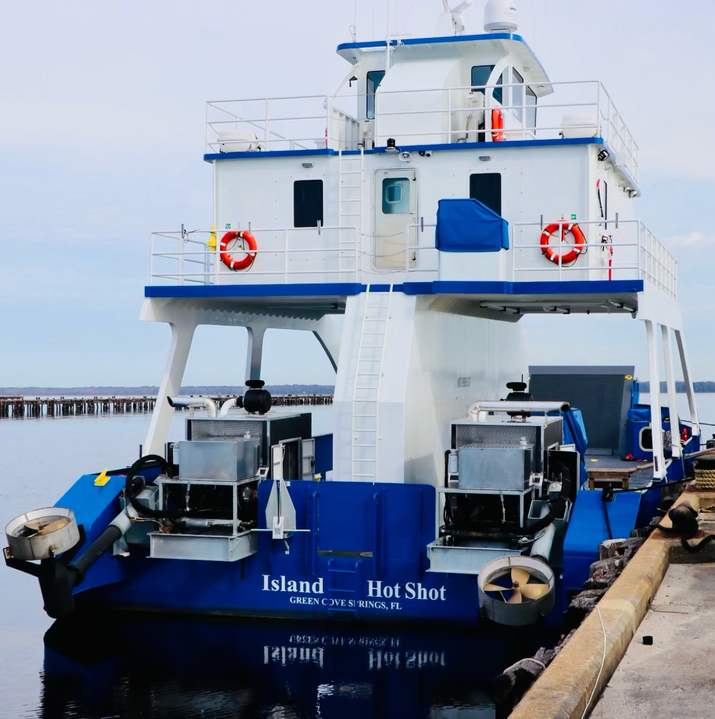 Stern of the Island Hot Shot at the dock showing twin outboard engine pods and the vessel name